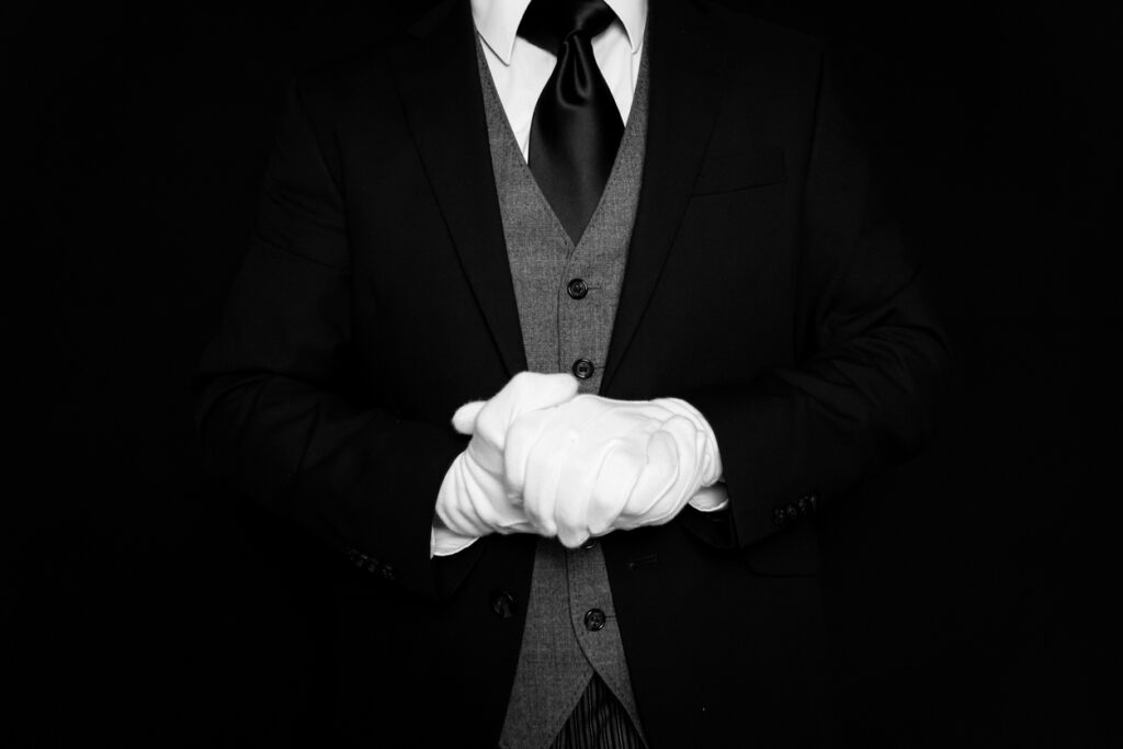At your service, a well-dressed butler with white gloves.